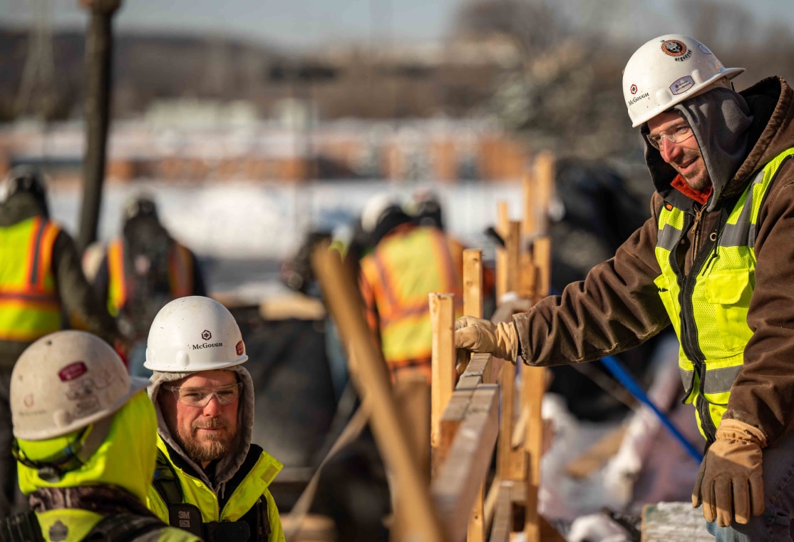 Three McGough construction workers talking on a job site wearing cold-weather gear