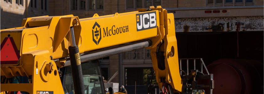 An excavator on a job site with McGough painted on its arm