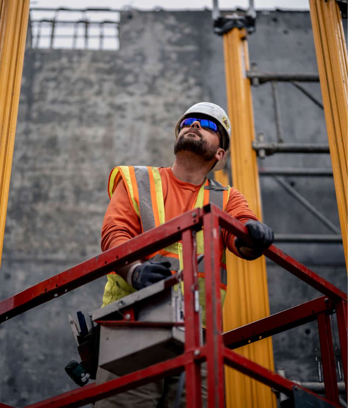 Bearded McGough construction worker in sunglasses on a platform inspecting work
