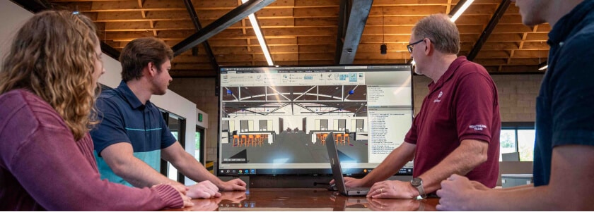 Four McGough project leaders around an office table looking at a 3D rendering on a screen