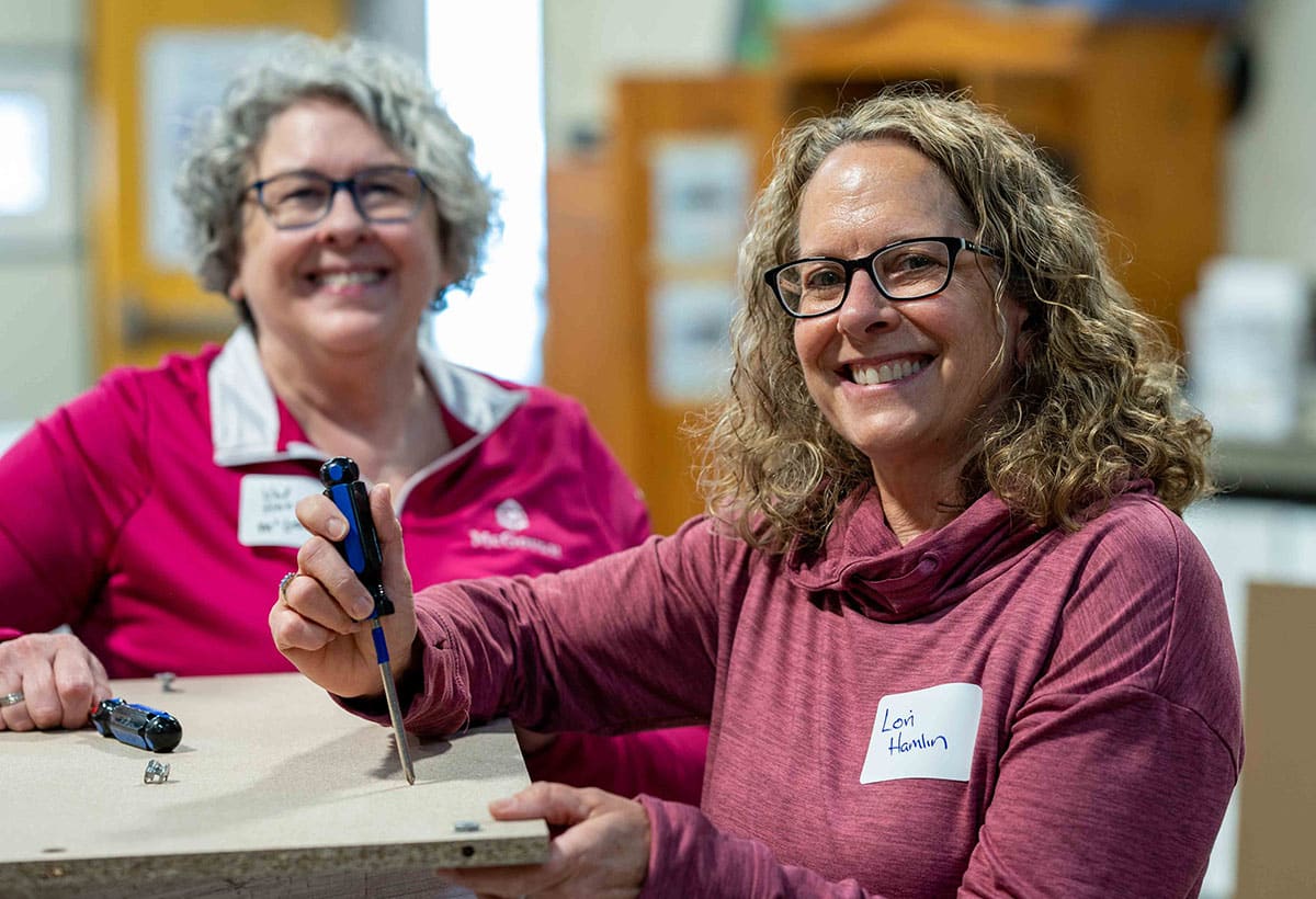 Two smiling female McGough employees working in an office