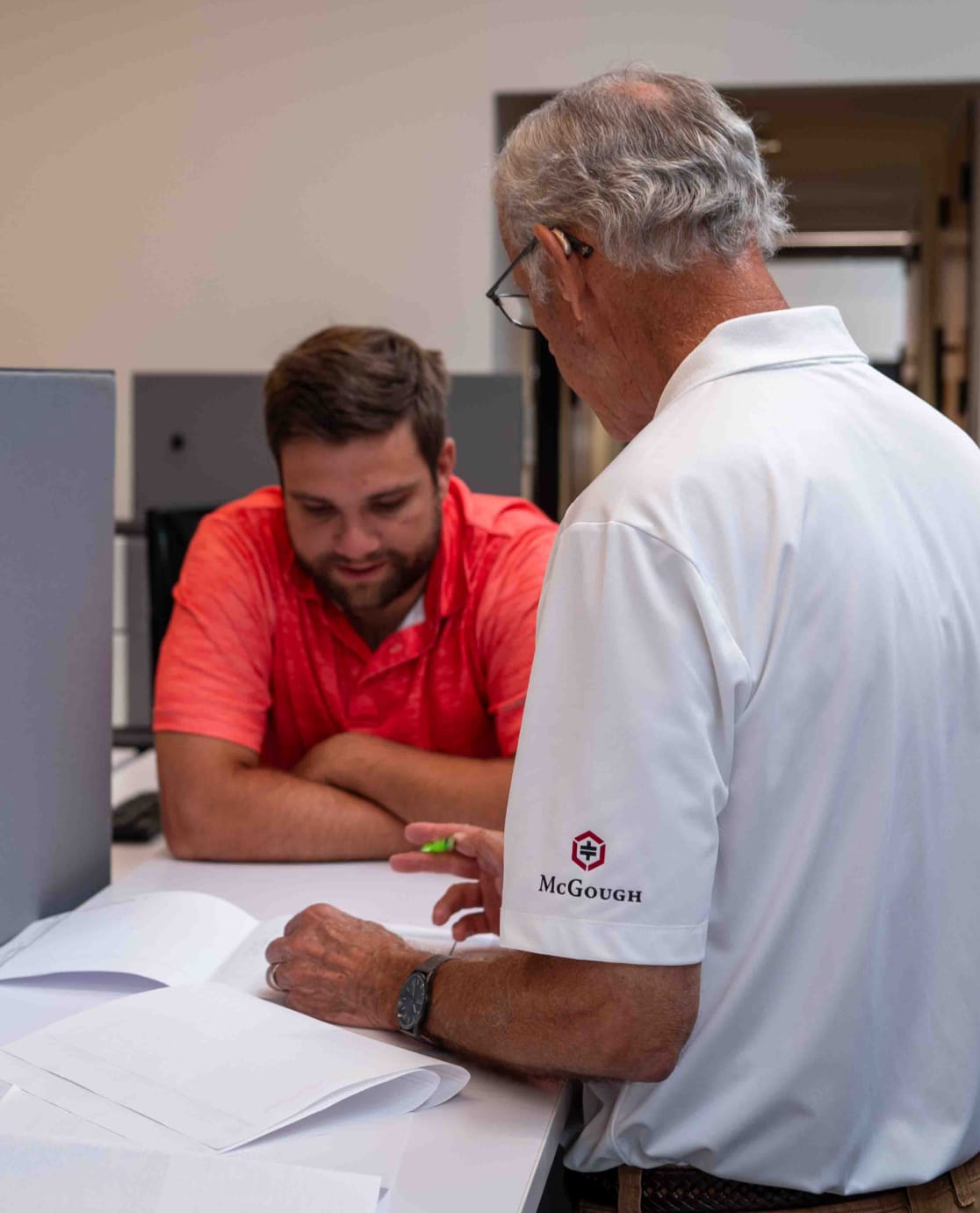 Two McGough workers in an office reviewing documents on a table