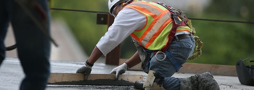A McGough construction worker smoothing concrete on a job site