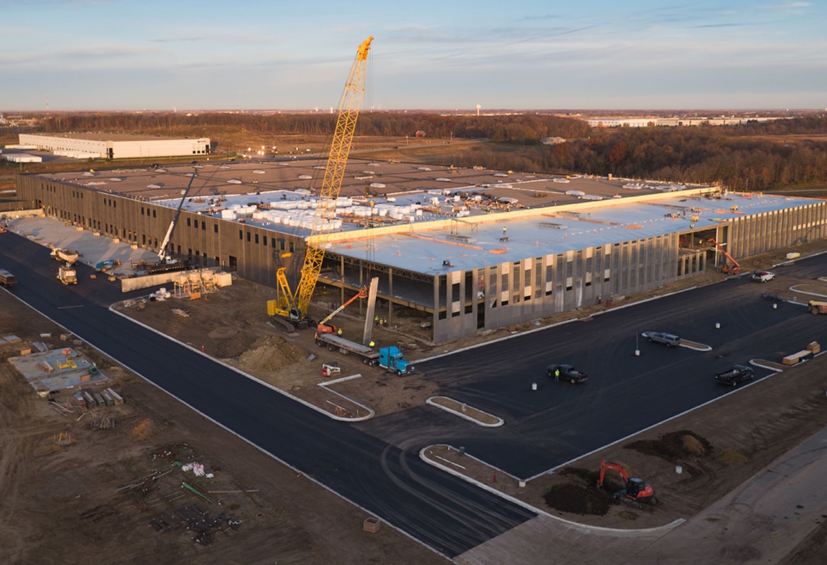 Arial image of a large warehouse/factory building under construction, with a crane in the foreground