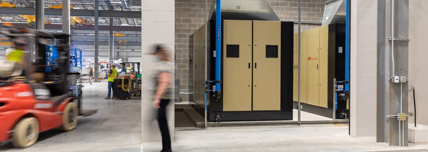 Interior image of a finished factory/warehouse, with a worker walking and forklift driving by