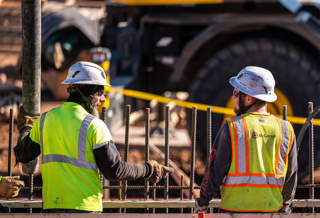 Three McGough construction workers talking on a job site wearing cold-weather gear
