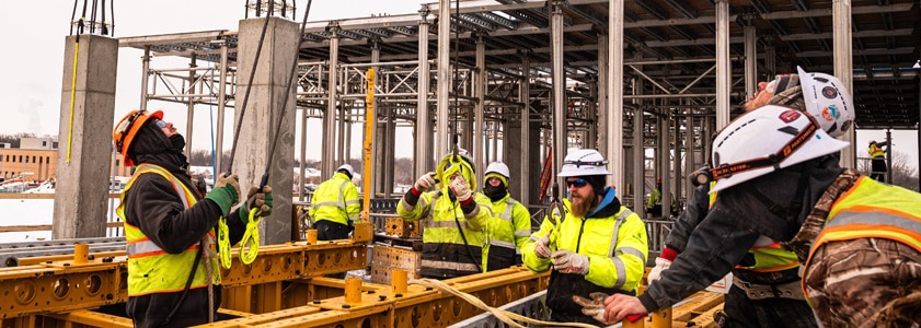 A team of McGough construction workers in safety gear gathered on a building's roof