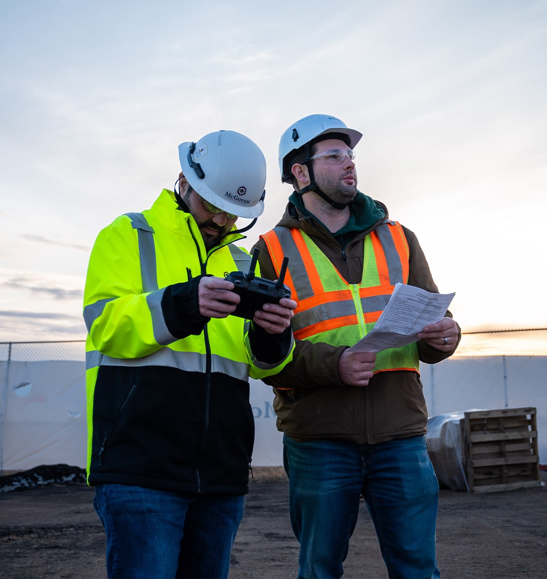 Image of male and female McGough project leaders in safety gear talking at a work site